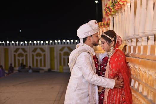 A traditional Indian couple shares an intimate moment during their vibrant wedding ceremony at night.