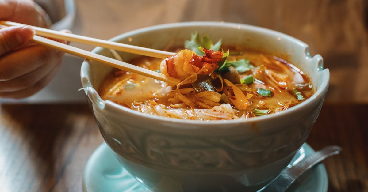 Schale mit Meeresfrüchte-Ramen, frischen Zutaten und dampfender Brühe in einem belebten Restaurant in Tokio