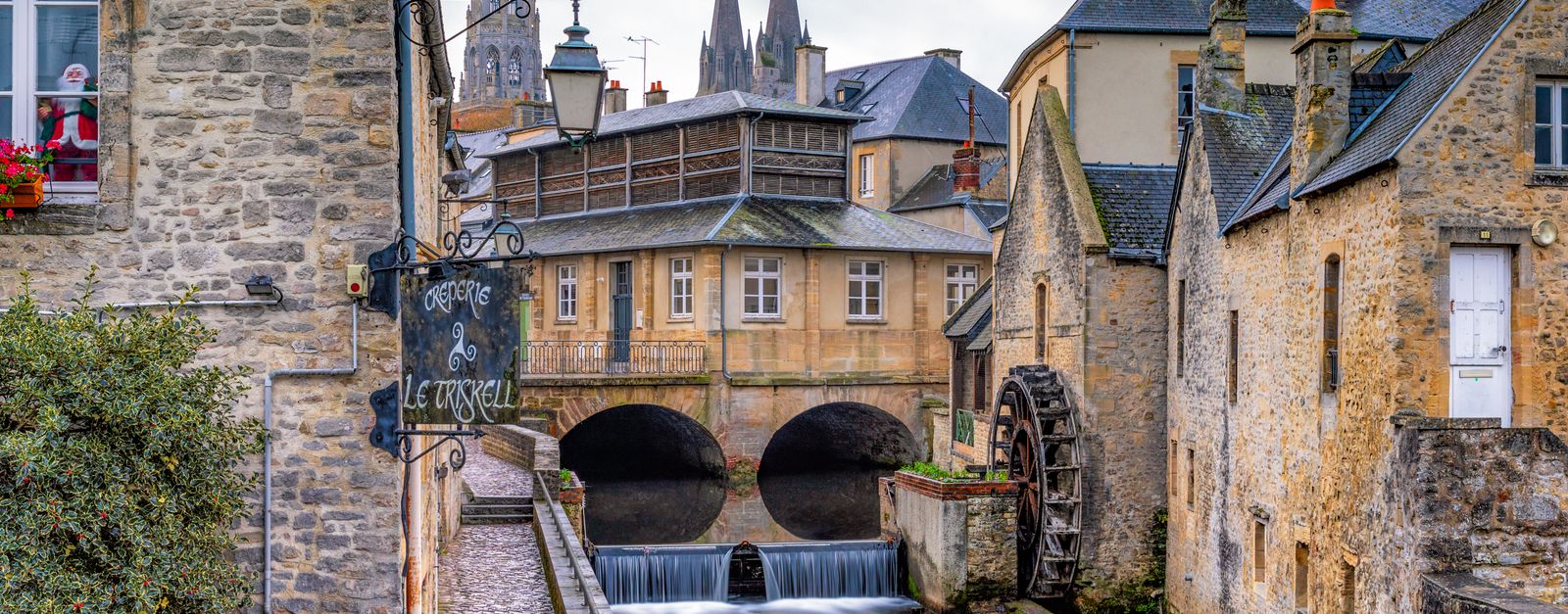Historic watermill on a picturesque canal in Bayeux, France, showcasing Normandy's charm.
