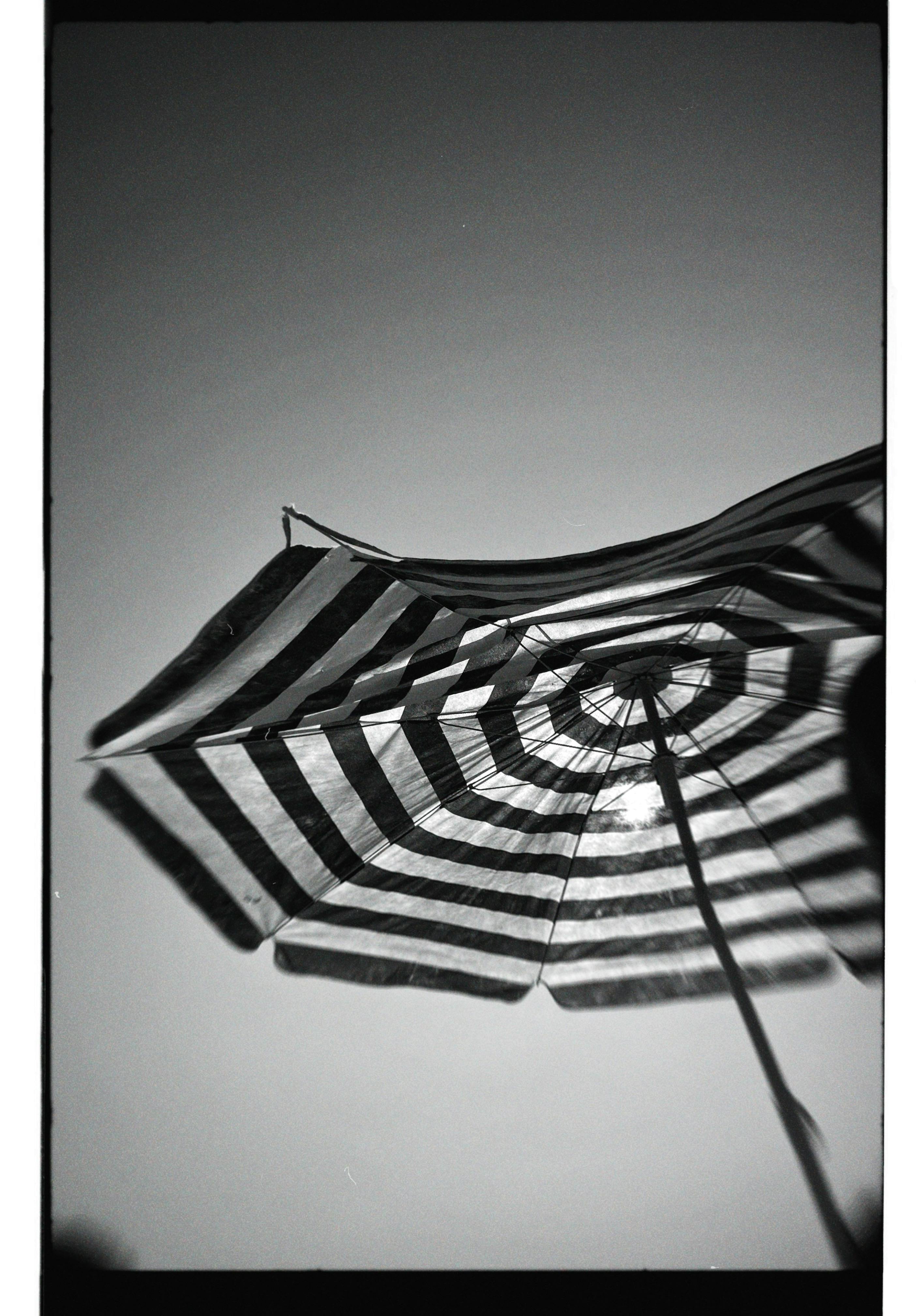 grátis Imagem em preto e branco de um guarda-sol listrado criando um contraste marcante com o céu. Foto profissional