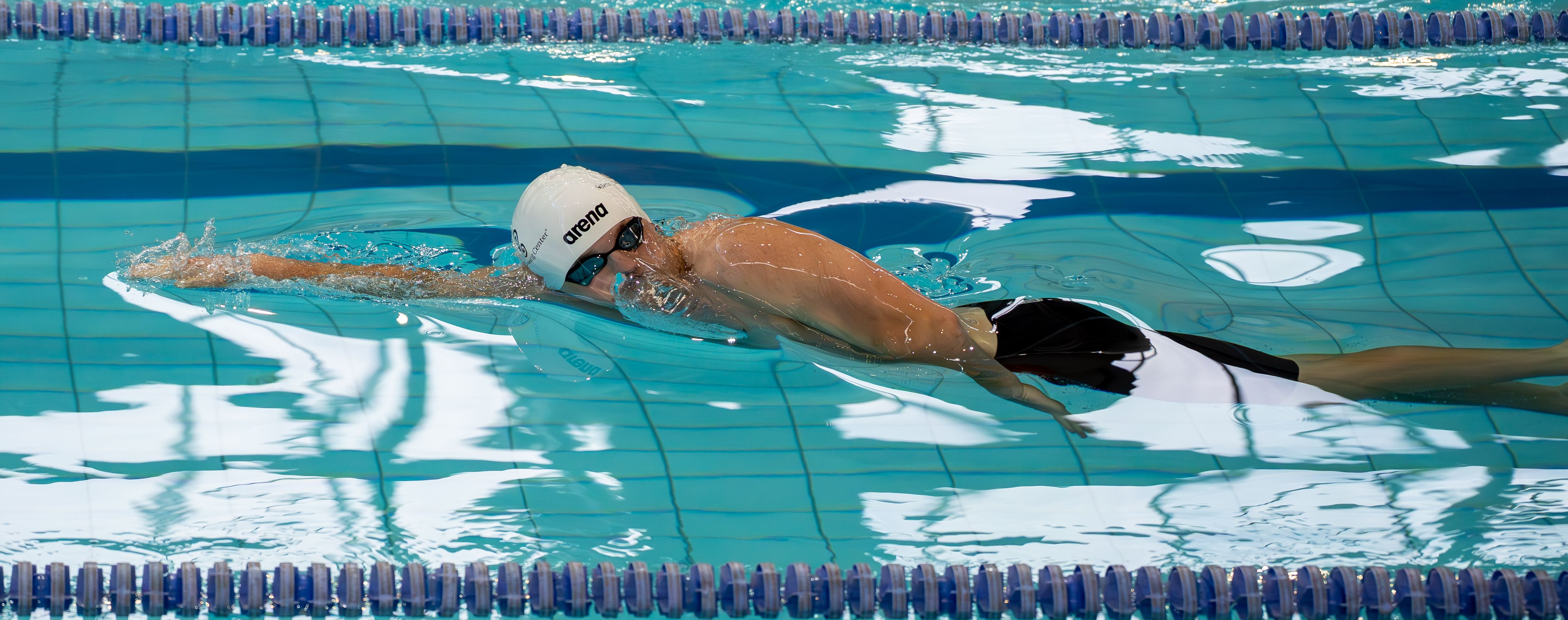 An athlete swimming freestyle stroke with focus in an indoor pool