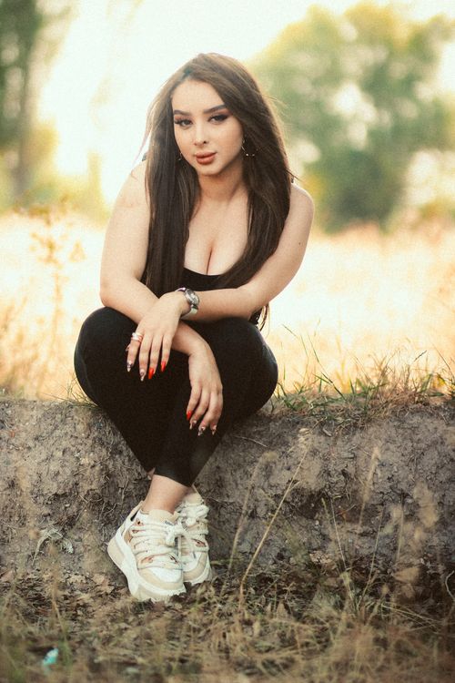 Free A stylish young woman poses outdoors in a natural setting, exuding confidence and elegance. Stock Photo