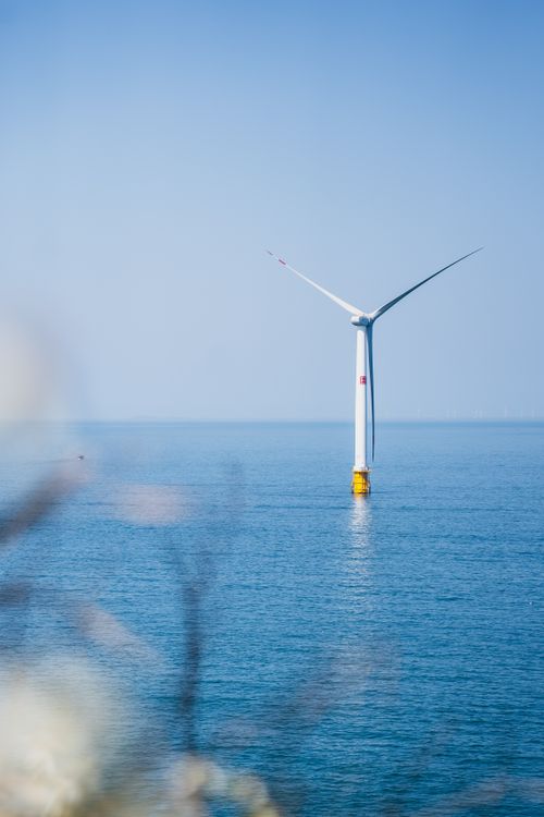 Free A single offshore wind turbine stands in peaceful ocean waters, captured on a clear day. Stock Photo