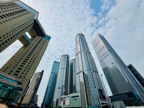 Low-angle view of modern skyscrapers in Tianjin under a partly cloudy blue sky.