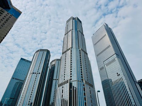 Tall modern skyscrapers of Tianjin under a partly cloudy sky, showcasing urban architecture.