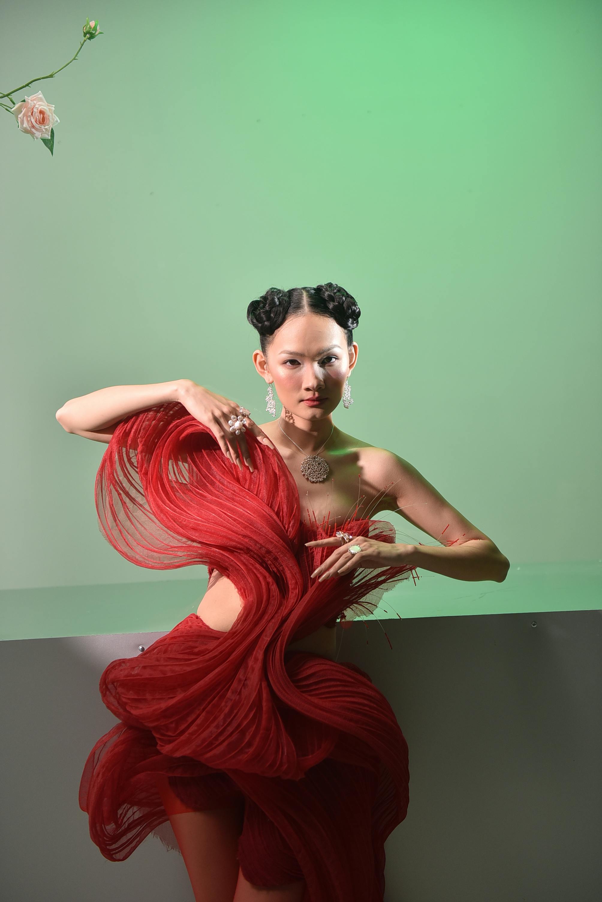 A striking portrait of a woman in an artistic red dress, set against a green background.