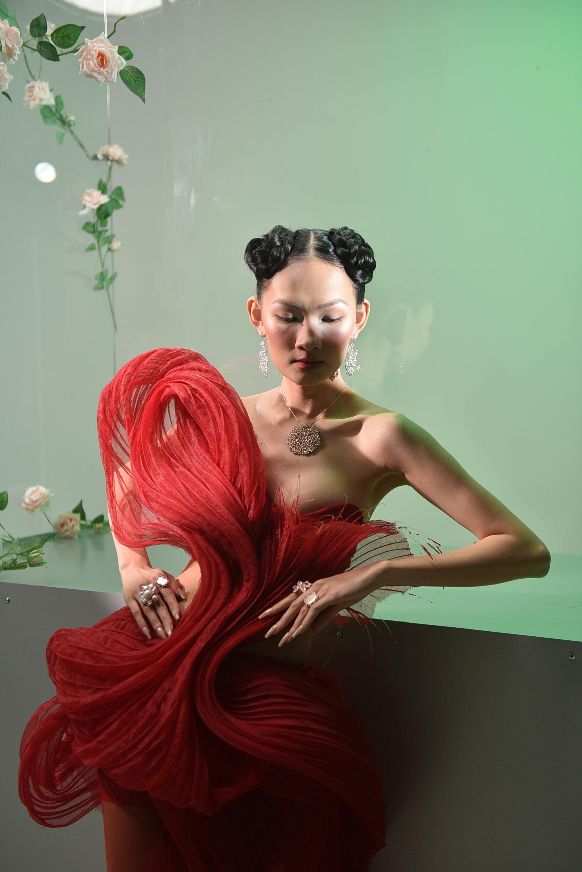 Striking portrait of a stylish woman in avant-garde fashion with red fabric and floral decor.