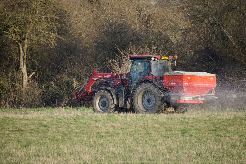 Lawn spreader being used to apply granular fertiliser evenly Lawn spreader being used to apply granular fertiliser evenly