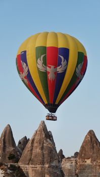 Colorful hot air balloon soars over Cappadocia's iconic rock formations at sunrise, a stunning travel adventure.