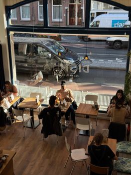 A lively indoor cafe setting with people dining and chatting on a sunny day.