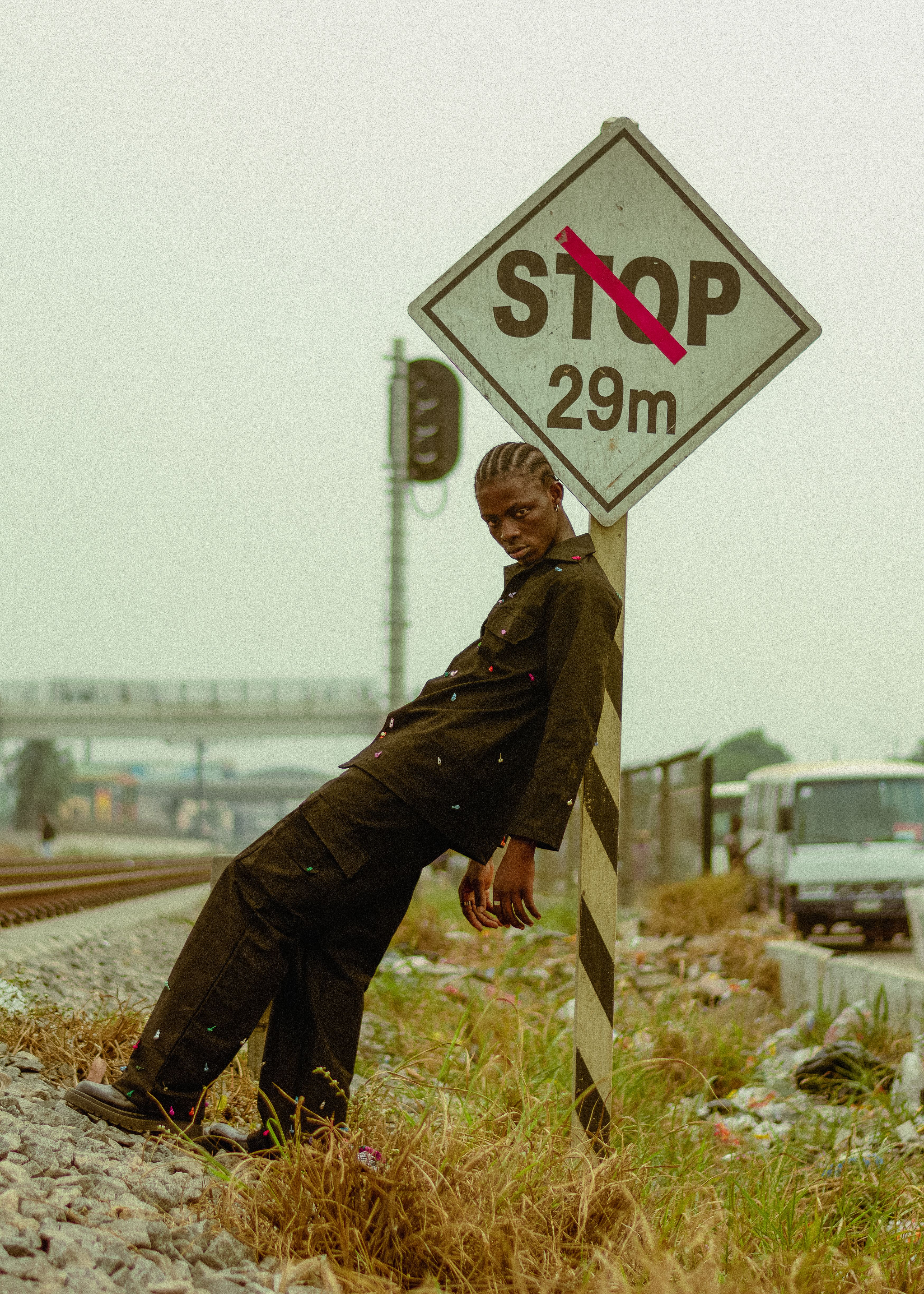 Young Man Leaning on Stop Sign by Railroad · Free Stock Photo