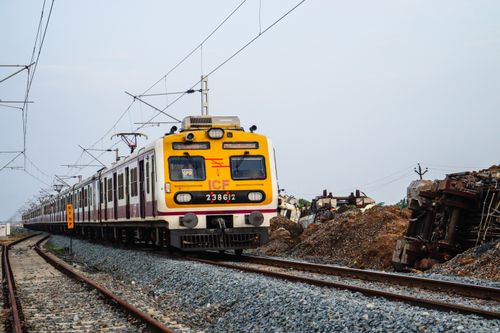 Free Local commuter train on tracks passing by wreckage, with clear sky backdrop. Stock Photo