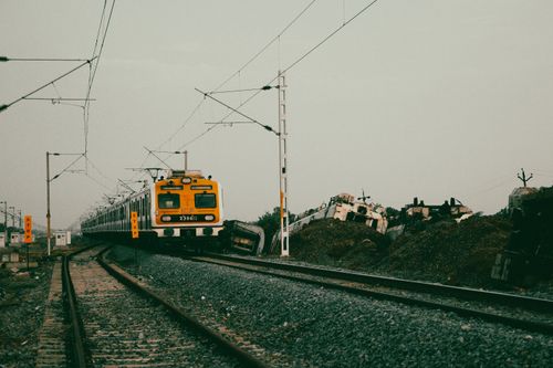 Free A commuter train navigates through railway tracks adjacent to a pile of abandoned train cars. Stock Photo