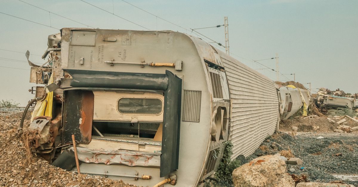 A derailed train lies overturned on a barren track, showcasing a scene of destruction.