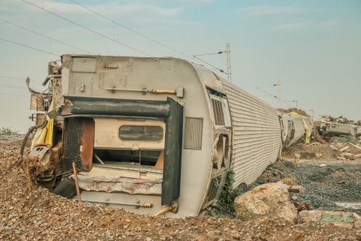 A derailed train lies overturned on a barren track, showcasing a scene of destruction.