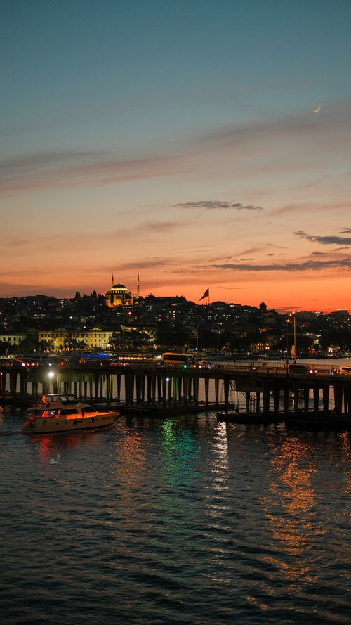 Free Boat passing under Galata Bridge at sunset in Istanbul with cityscape view. Stock Photo