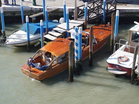 Wooden boats moored along the iconic canals of Venice, Italy on a sunny day.