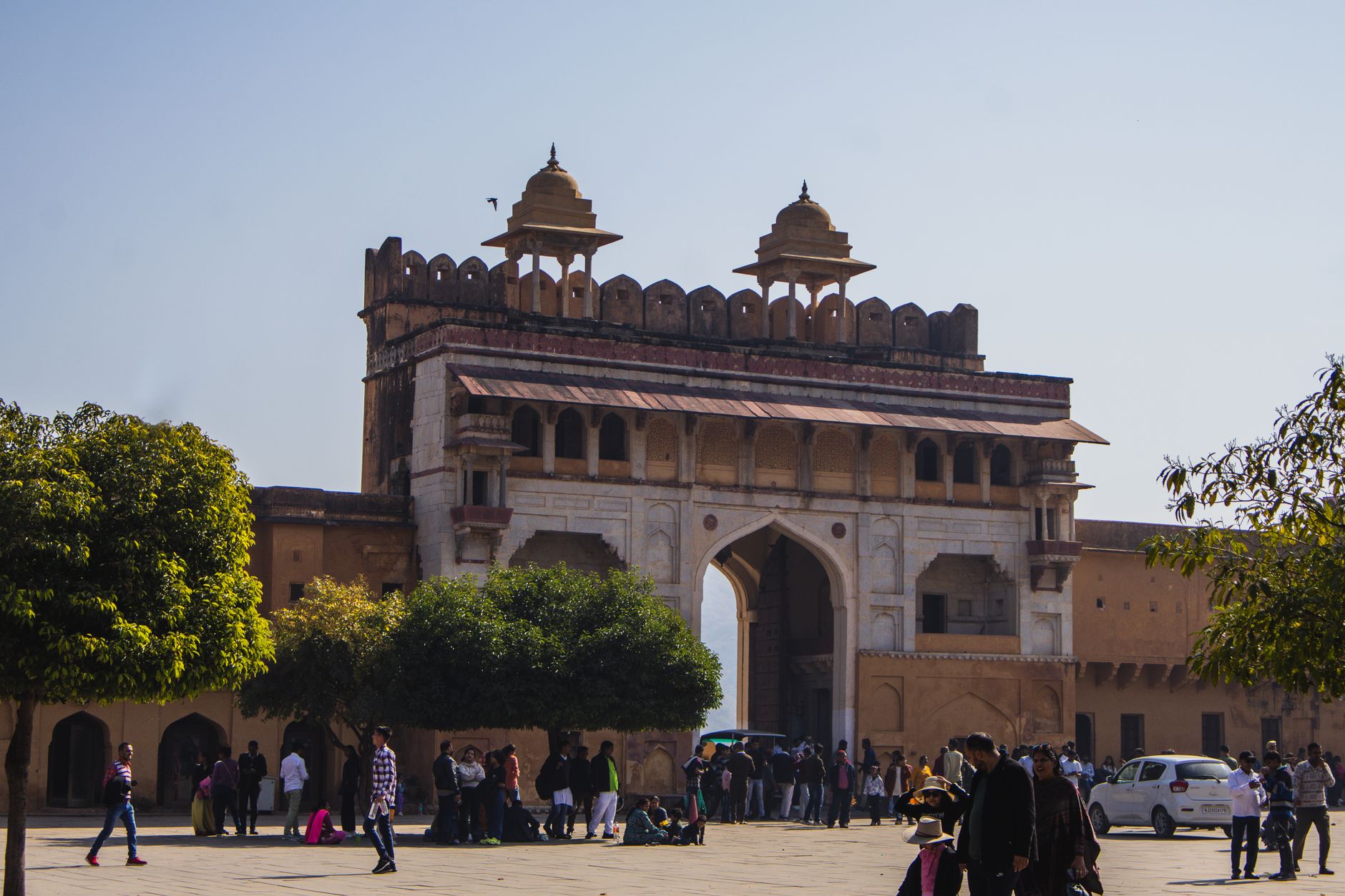 Photo of Amber Fort gate bustling with tourists under a clear blue sky.