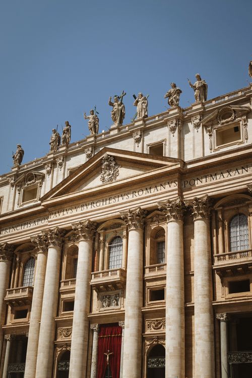 Free Close-up of St. Peter's Basilica's intricate facade with statues under a clear blue sky. Stock Photo
