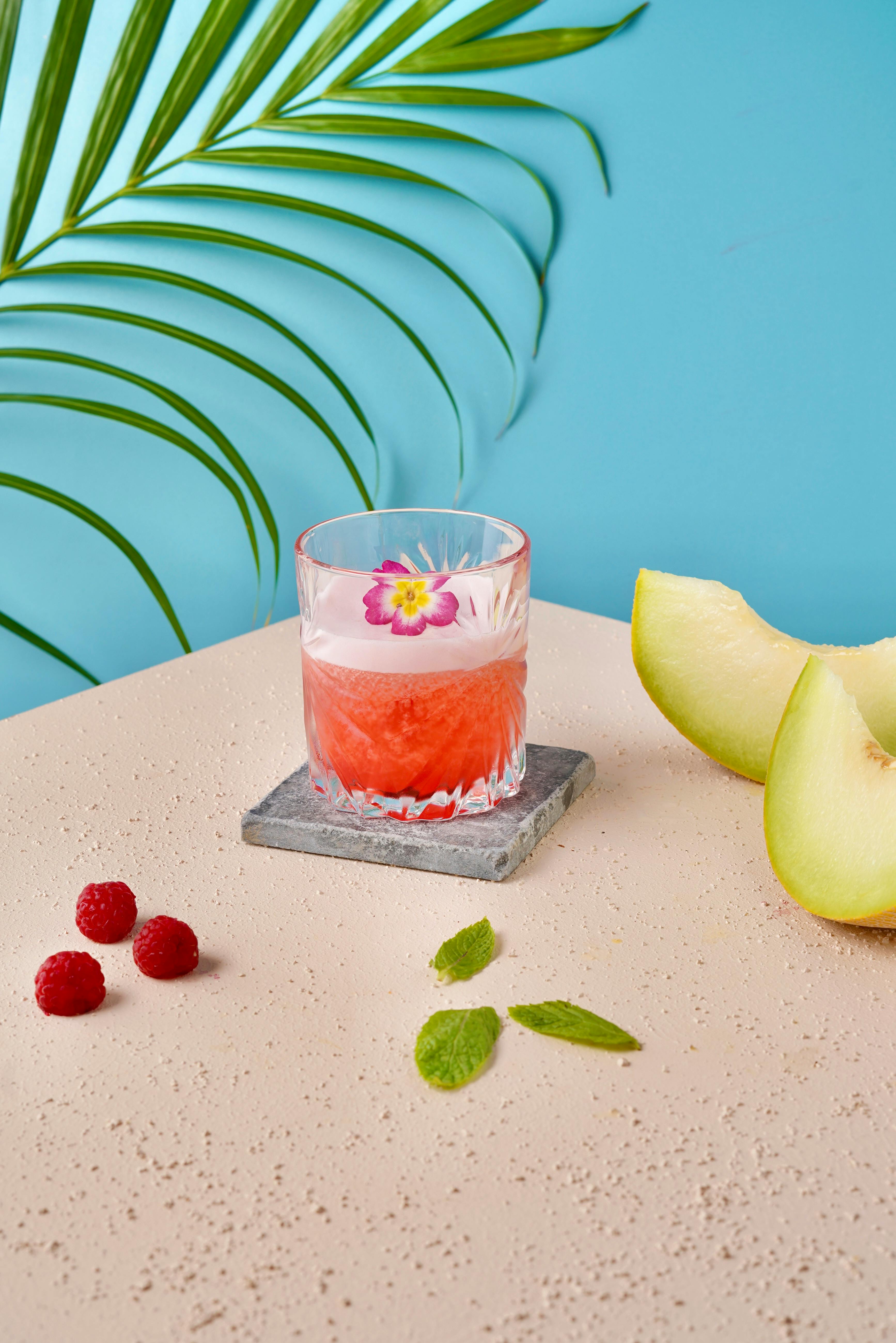 Vibrant summer drink with melon, raspberries, and mint on a stylish setting.