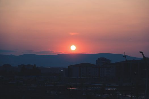 A stunning sunset casting vibrant colors over the silhouette of an urban cityscape.