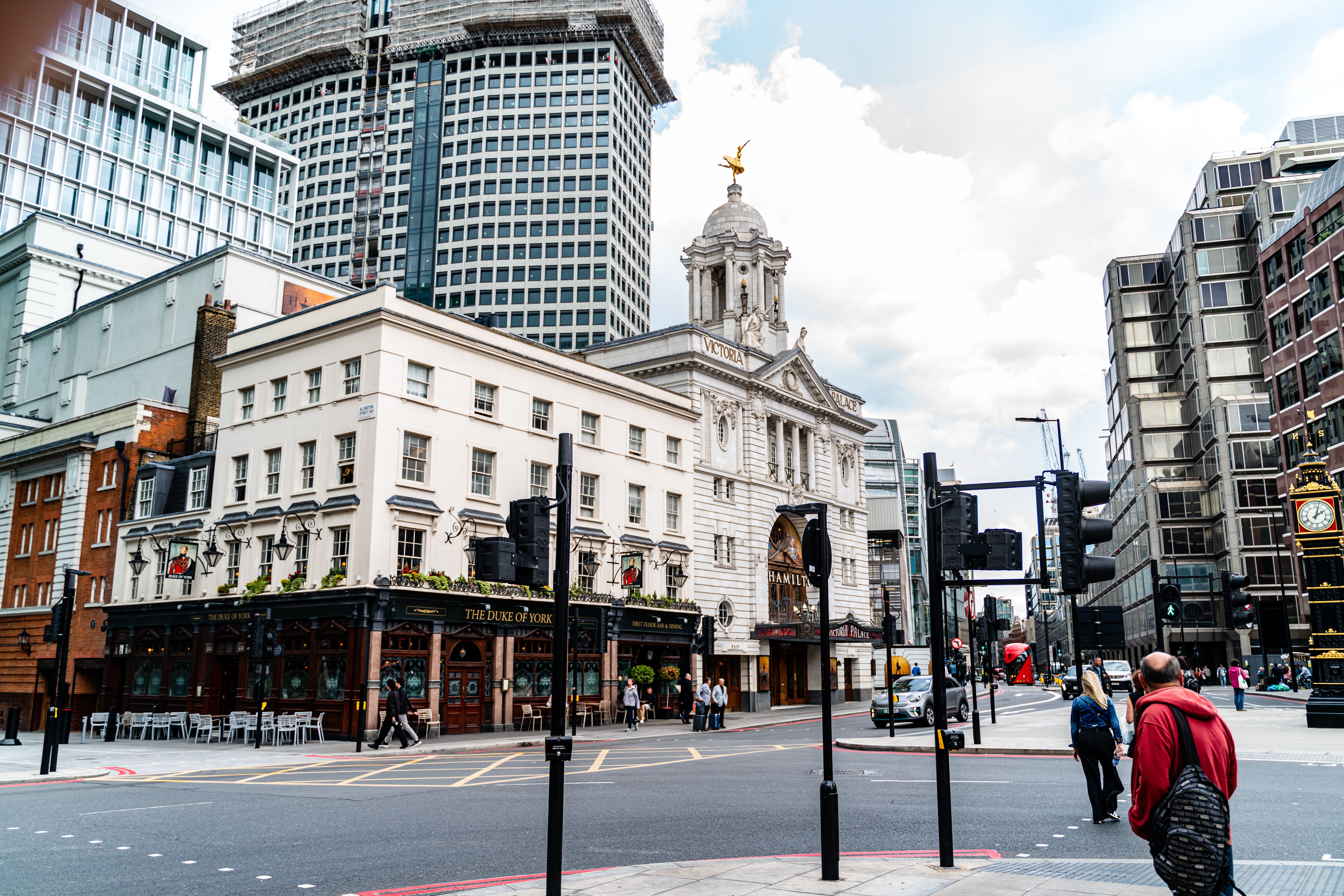 Street view of the iconic Victoria Palace Theatre and nearby buildings in London, England.