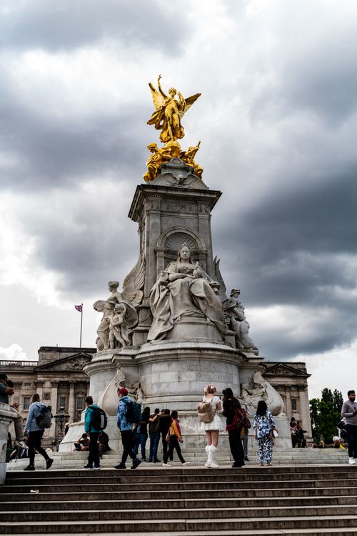 Free Tourists gather around the Victoria Memorial in London, England, beneath dramatic cloudy skies. Stock Photo