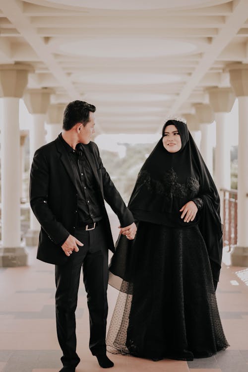 gratis Man In Zwart Pak Hand In Hand Met Vrouw Die Zwarte Hijab Draagt Stockfoto