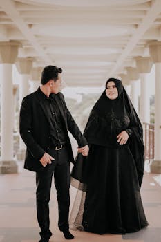 一对时尚情侣穿着传统服装，在大拱门下手牵着手