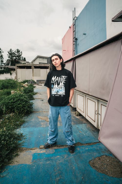 Free Portrait of a man in oversized streetwear and denim, captured outside on a cloudy day. Stock Photo