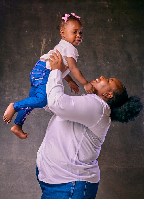 Free Happy mother lifting her smiling baby girl, expressing love and affection indoors. Stock Photo