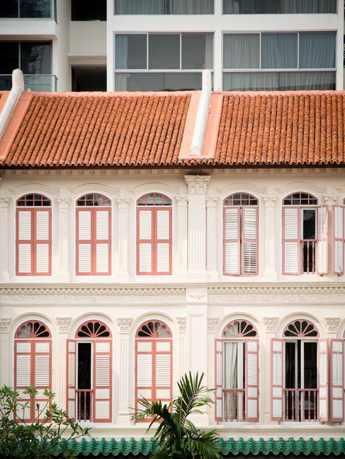 Free Elegant colonial building with red shutters and roof against a modern backdrop depicting architectural contrast. Stock Photo
