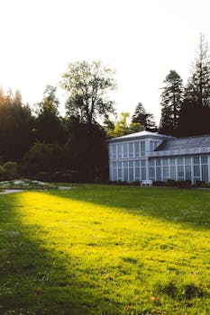 Tranquil view of a historic German garden at sunset, featuring lush green lawns and vintage architecture.