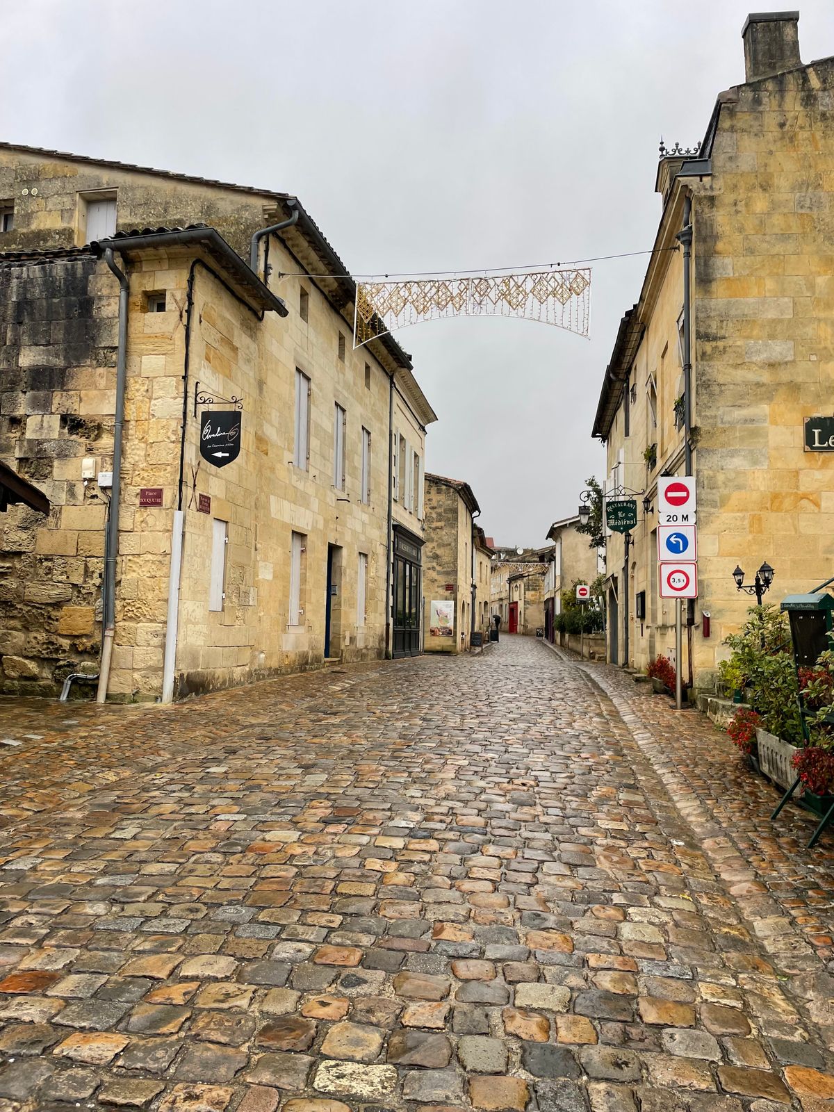 A wet cobbled lane between honey-stone houses in Saint-Émilion