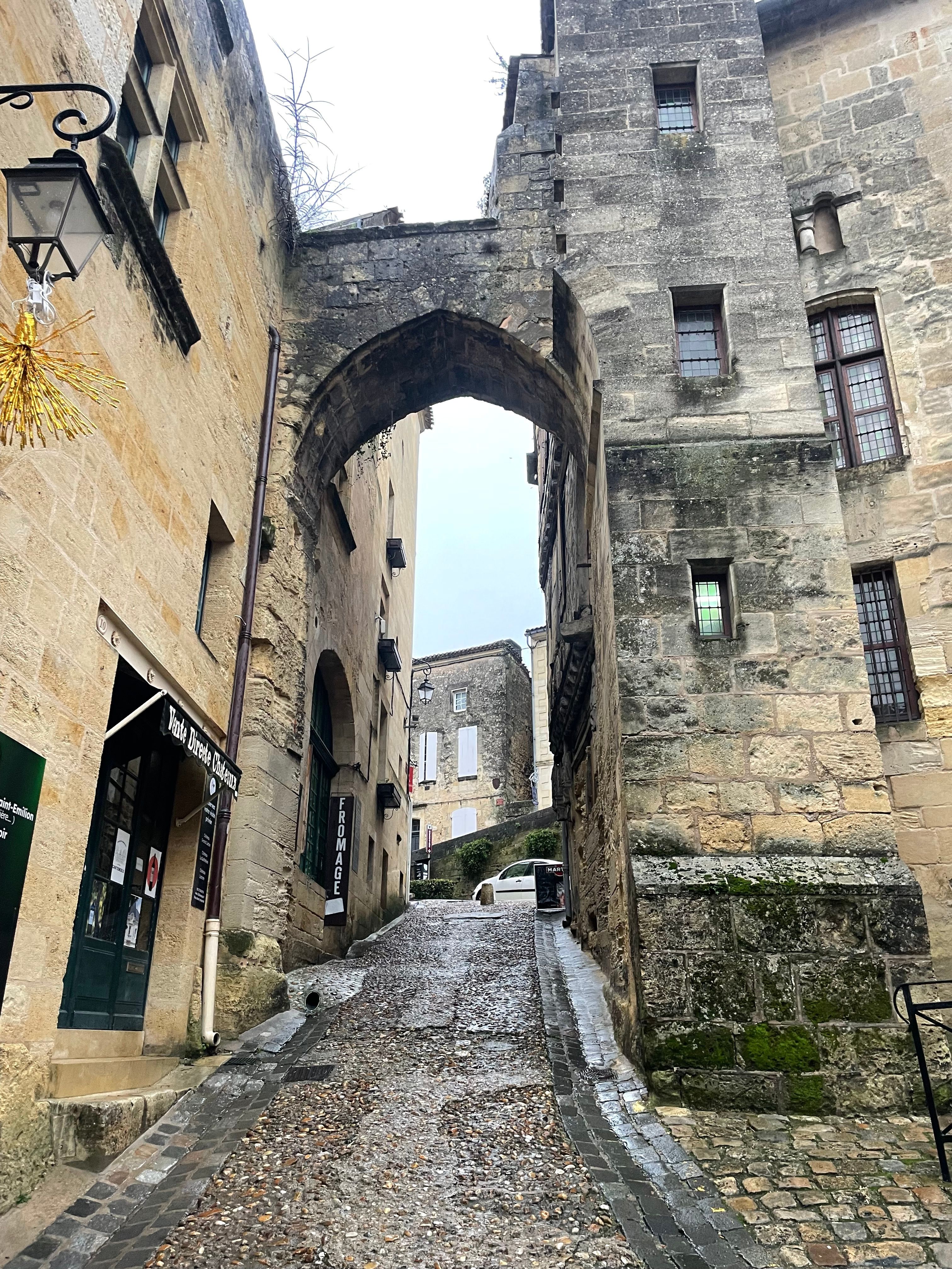 Charming medieval street with stone archway in historic Saint-Émilion, France.