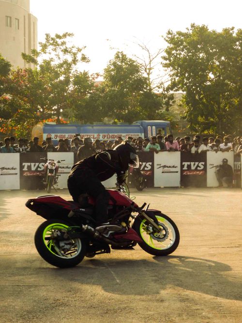 Free Motorcyclist performing thrilling stunt before an enthusiastic outdoor crowd. Stock Photo