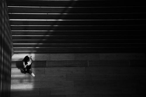 Free A lone person walking on an empty staircase in stark black and white lighting. Stock Photo