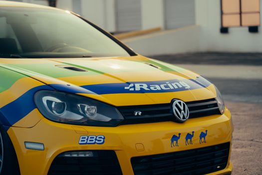 Vibrant racing car with custom decals in outdoor setting during daytime.