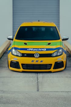 Vibrant yellow race car with striking decals parked in an industrial garage setting.