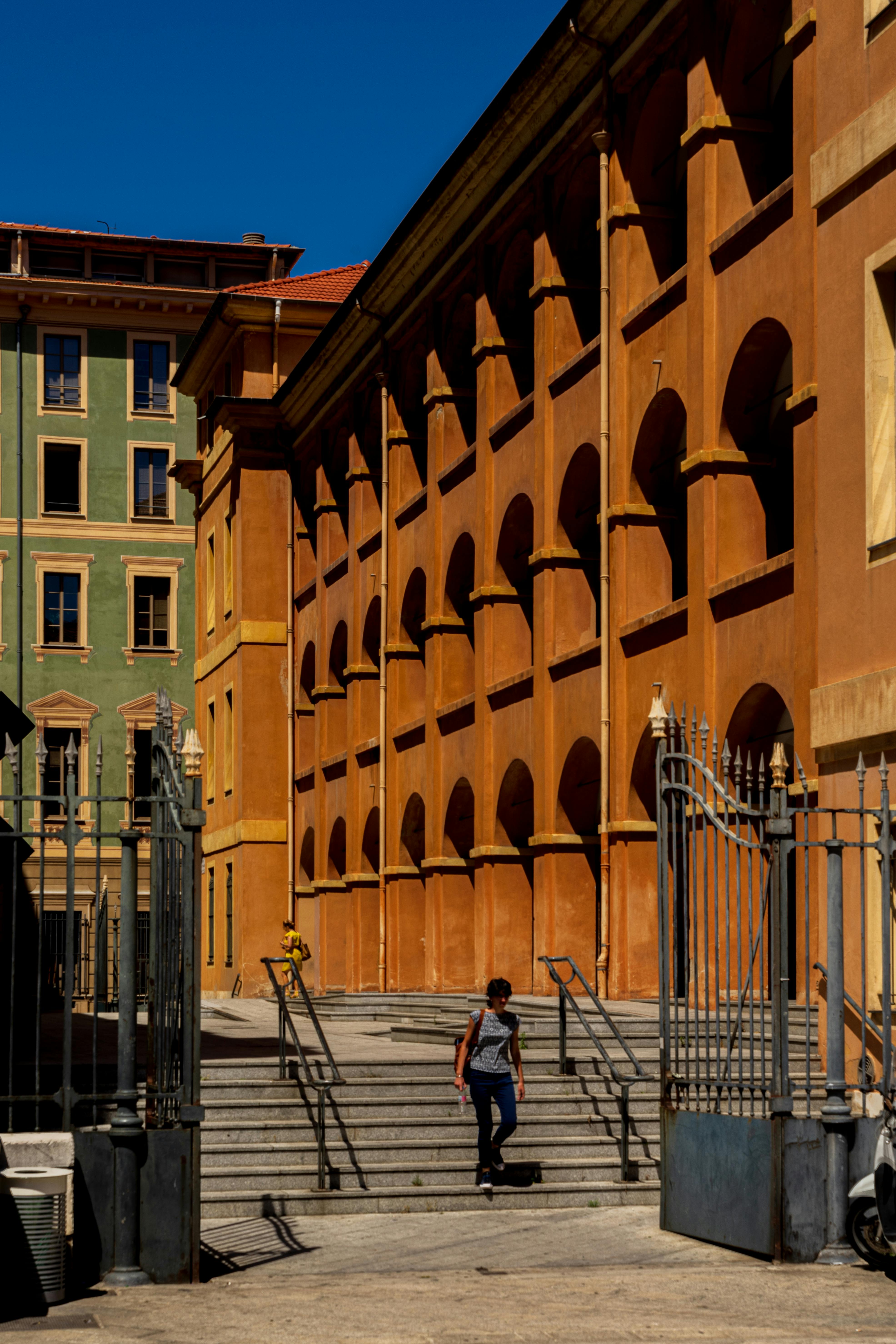 A person walks up stairs beside colorful buildings on a sunny day.