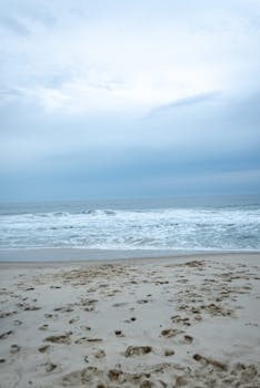 Serene beach image showcasing soft sand and gentle ocean waves under a peaceful sky.