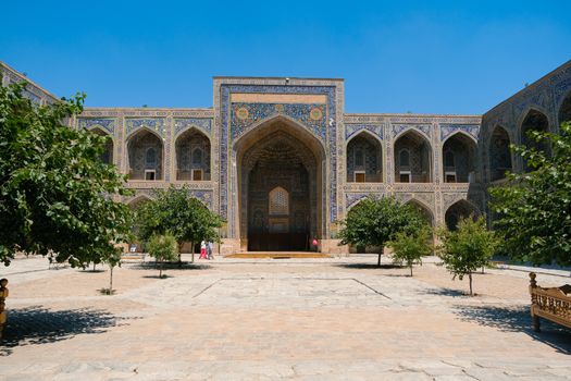 Stunning facade of an Islamic architectural landmark with intricate tilework under a clear blue sky.