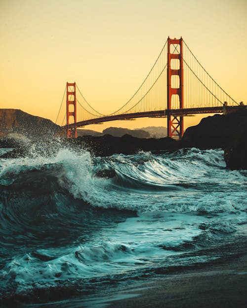 Free Low Angle Shot Of Strong Waves Crashing On The Shores Under Golden Gate Bridge Stock Photo