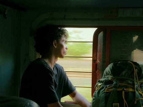 A man gazes out the window of a moving train in Kerala, India, embodying the spirit of travel and adventure.
