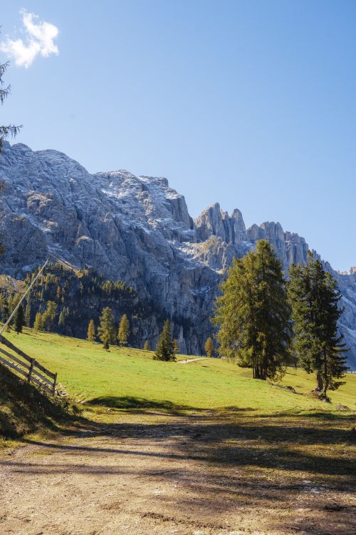 Free A picturesque view of rugged mountains with a lush green meadow in the foreground. Stock Photo