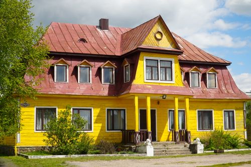 Free Bright yellow wooden house with red roof in Grodno Region, Belarus under blue sky. Stock Photo