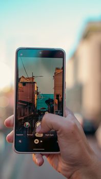 A smartphone capturing the picturesque streets of Genoa, Italy, during sunset.