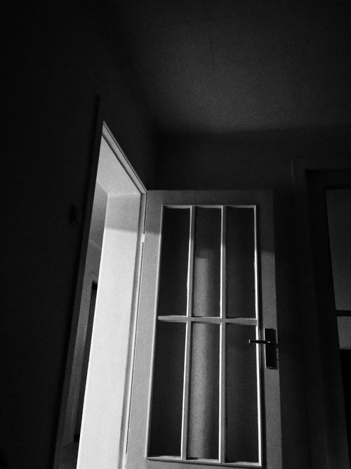 Free A monochrome image of an open door in a shadowy room casting dramatic shadows. Stock Photo