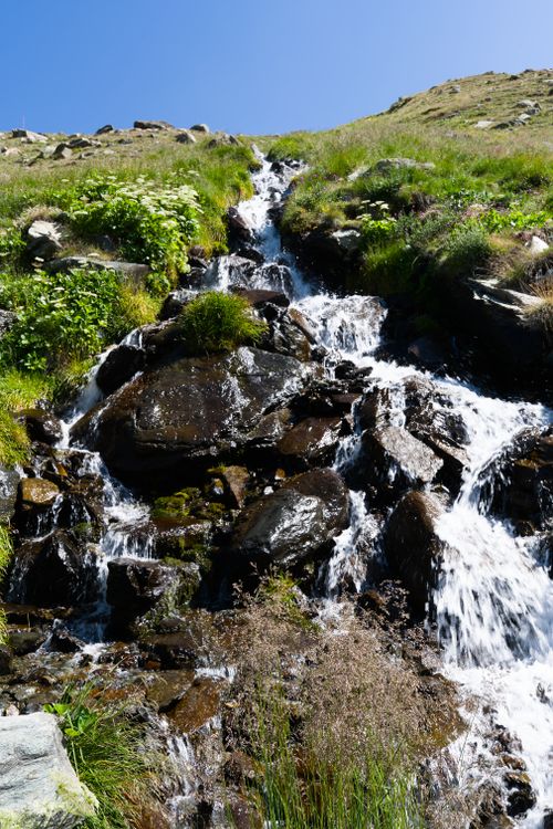 Free Beautiful alpine waterfall cascading over rocks in Swiss mountains, perfect for travel and nature themes. Stock Photo