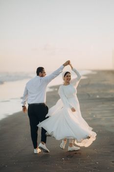 Couple dances on a serene beach in Egypt during a beautiful sunset, capturing love and elegance.